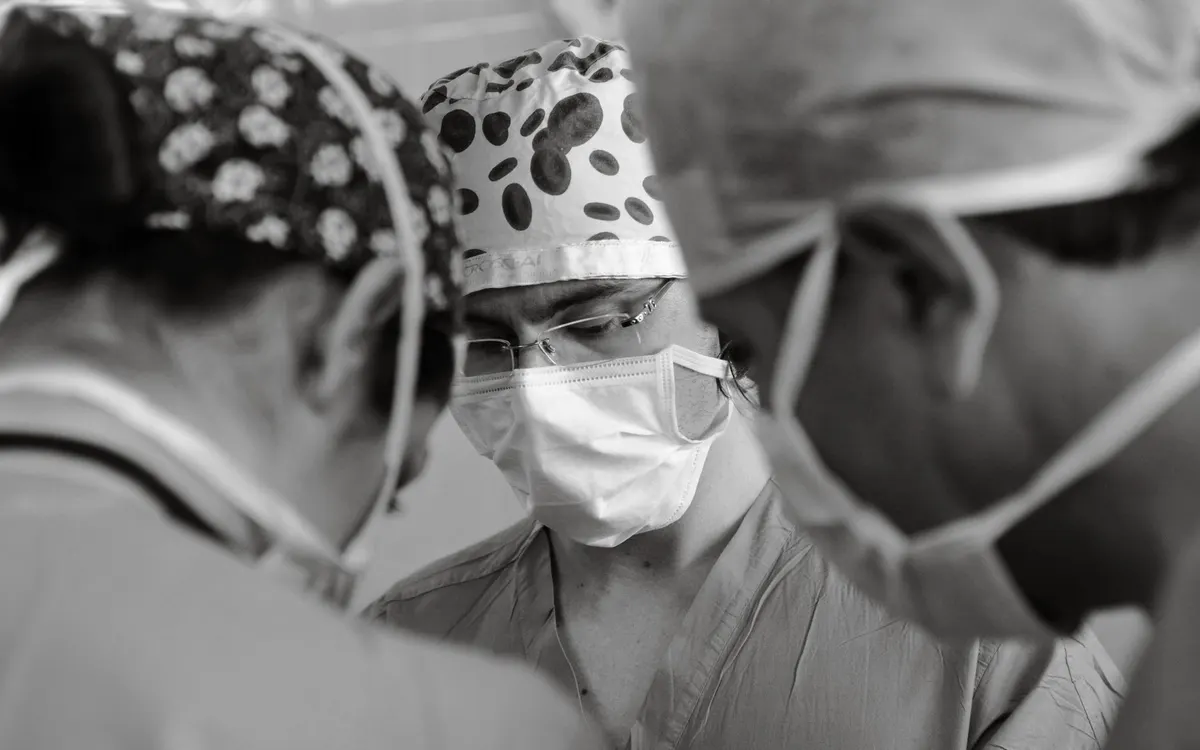 An anaesthetist monitoring a patient in an operating theatre.