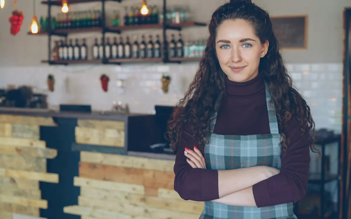 A cafe owner standing with her arms folded in front of the counter