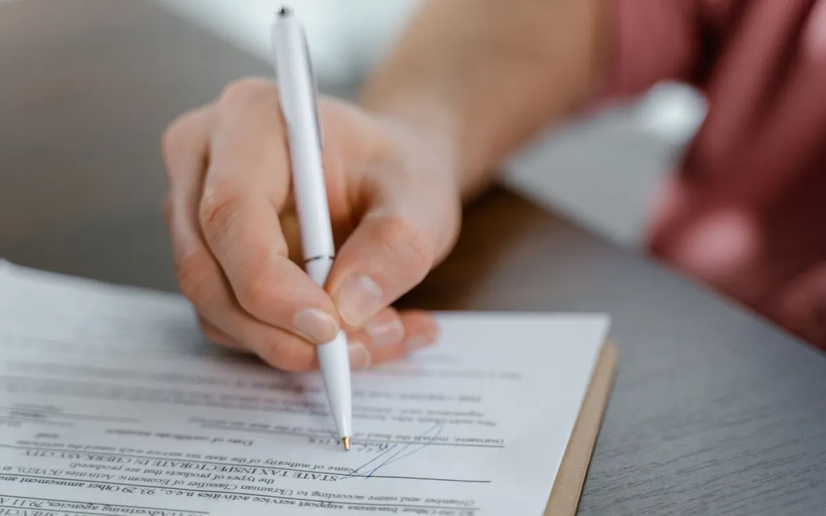 Signing official documents with a pen.