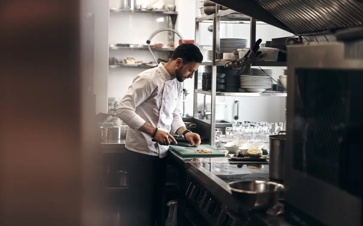 Chef in whites preparing food at a commercial kitchen bench