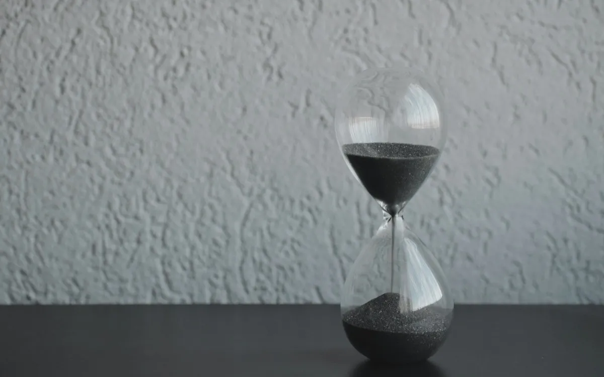 Hourglass with sand running through, sitting on a desk