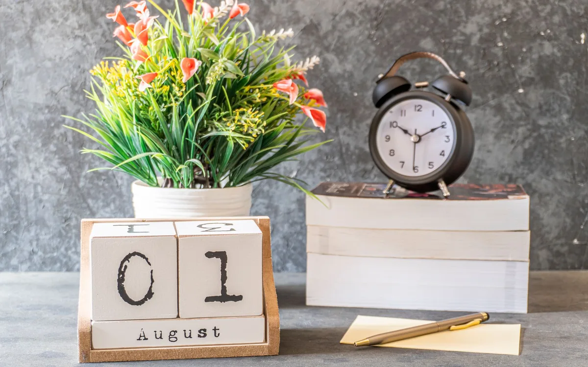 A desk calendar and alarm clock on a stack of books
