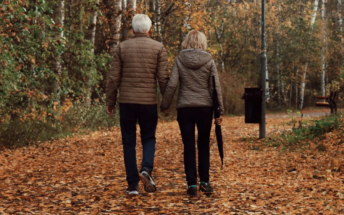 A couple walking together outdoors in autumn.