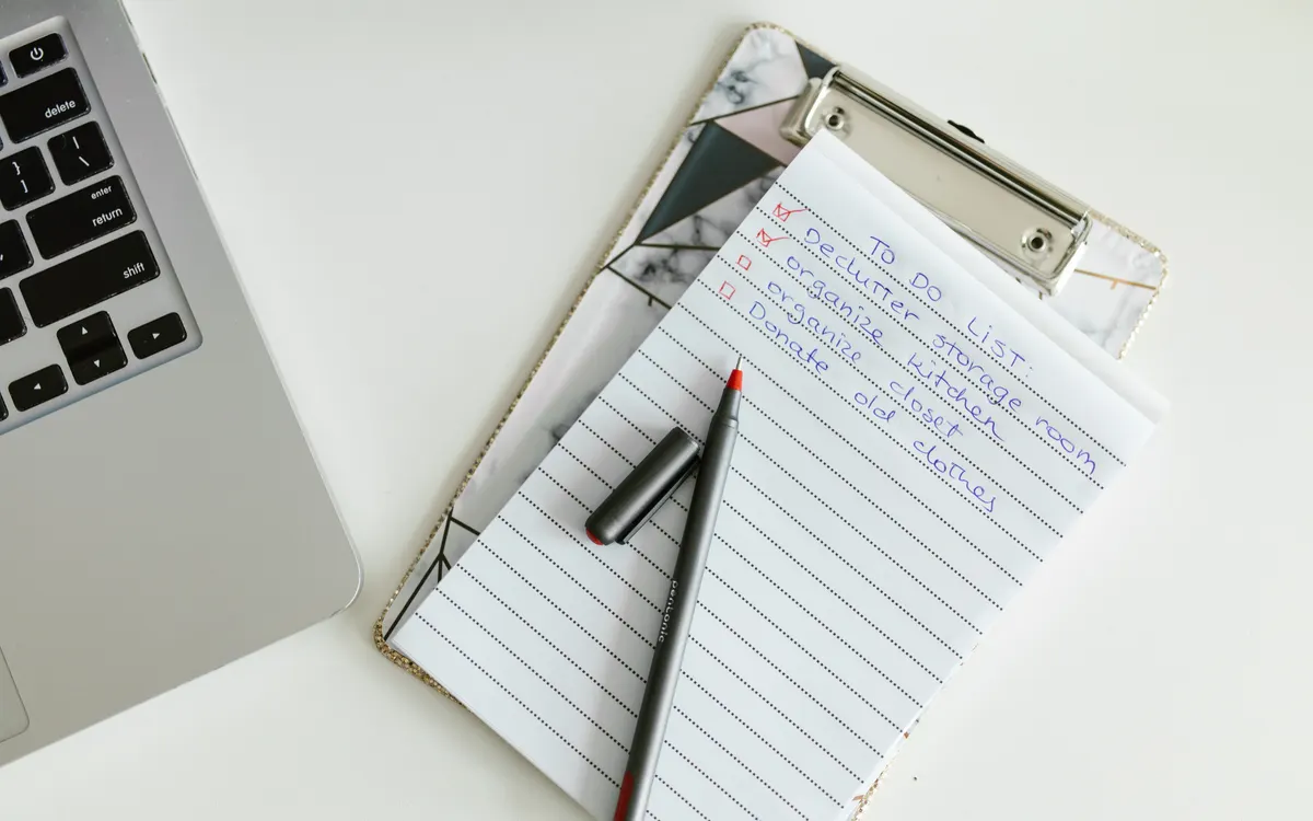 A checklist on a clipboard beside a laptop.