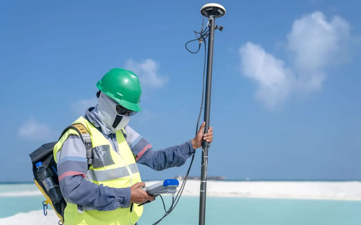 A surveyor using mapping equipment in the field.