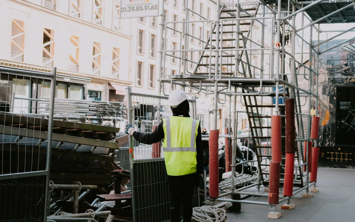 A construction worker in a high-visibility vest at a worksite.