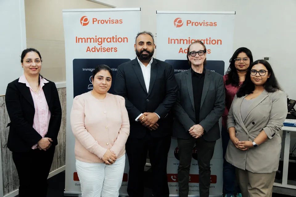 Provisas immigration advisers team at the Manukau office, with branded Immigration Advisers pull-up banners.