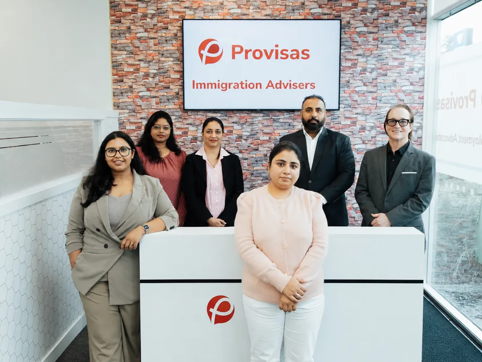 Provisas team at the Manukau office reception, with a team member at the front desk and the supporting team behind.